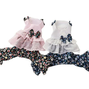 Two floral dog rompers in white and pink with floral patterns and bows on a white background