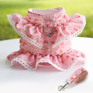 Pink floral dog harness and leash set on a white surface with grass background