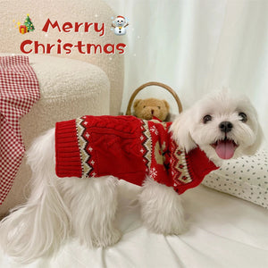 White dog wearing a red Christmas sweater on a couch with 'Merry Christmas' text and decorations.
