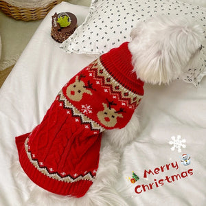 Red knitted dog sweater with reindeer pattern on a white surface, featuring a 'Merry Christmas' text.