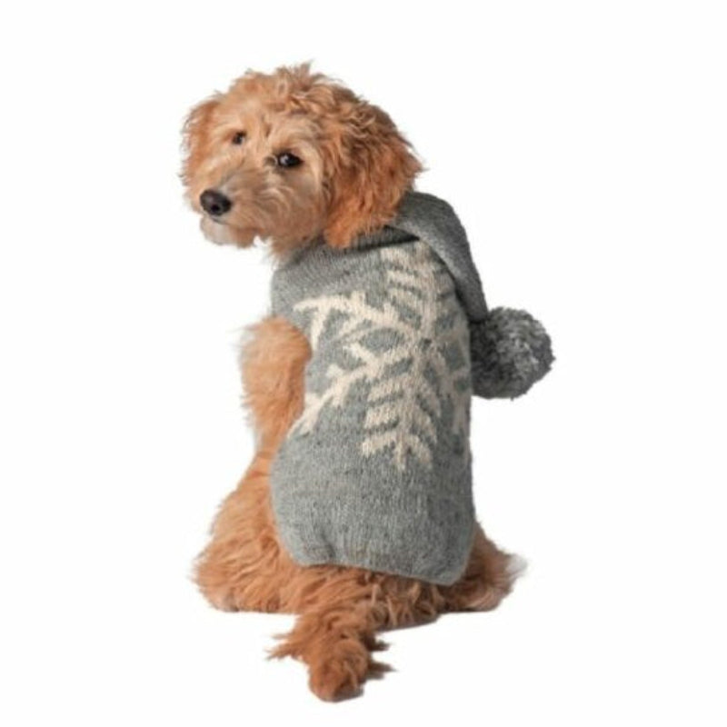 A doodle wearing a gray knit pet sweater with a white snowflake pattern and a pom-pom hood  against a white background.