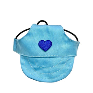 Blue dog hat with a heart-shaped patch on a white surface with decorative items.