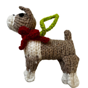 Knitted Boxer dog ornament with a red scarf and green tag on a white background