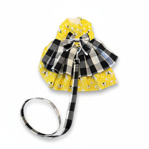 Yellow pet dress with black and white checkered bow and leash white surface