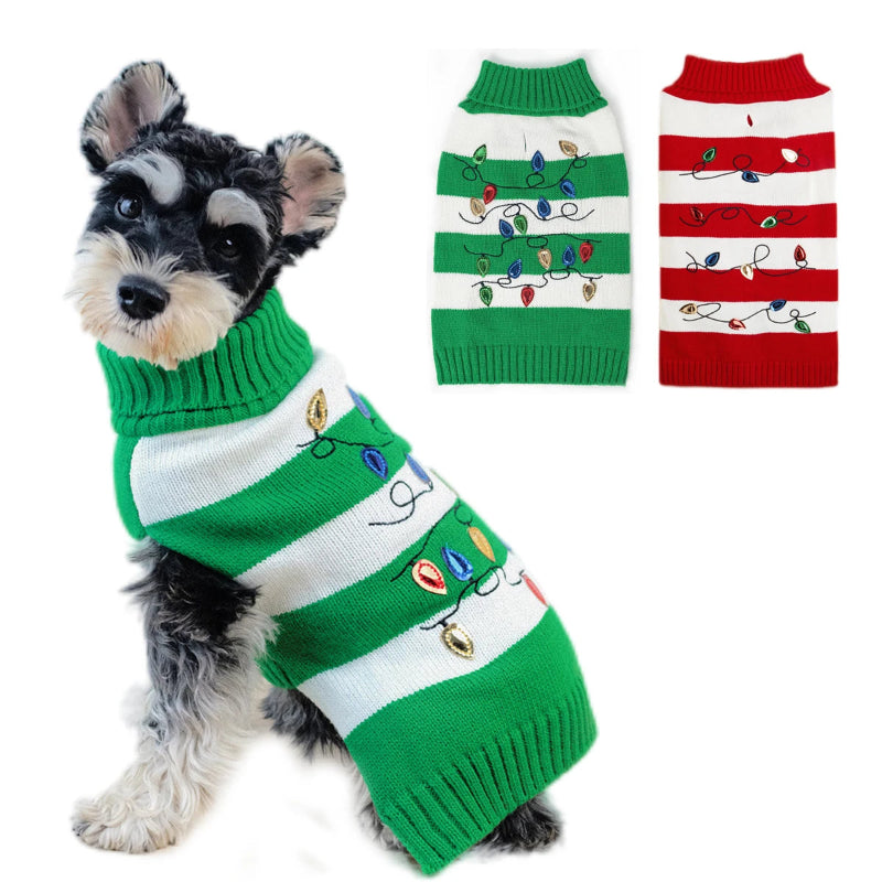 Dog wearing a green and white striped sweater with Christmas lights, next to two other sweaters.