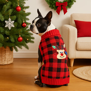 Boxer Dog wearing a red and black checkered sweater with a reindeer design, standing in a festive room with a Christmas tree and wreath.