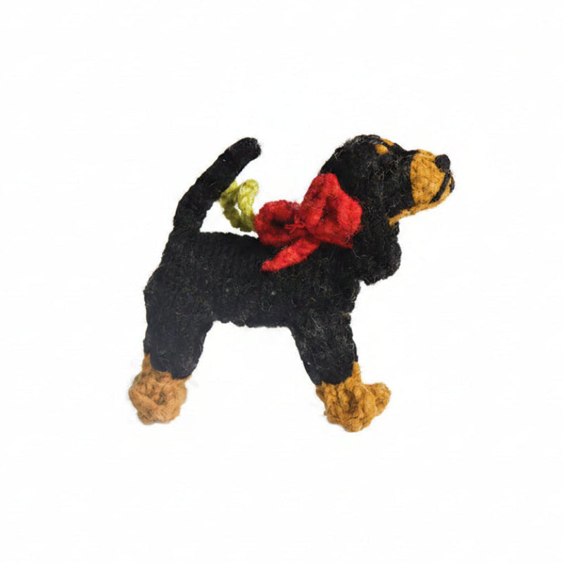 Knitted Coonhound dog ornament with a red bow and green tag on a white background