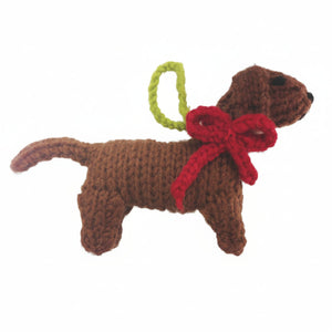 A brown knitted dachshund dog ornament with a red bow and a green hanging loop, shown against a plain white background.