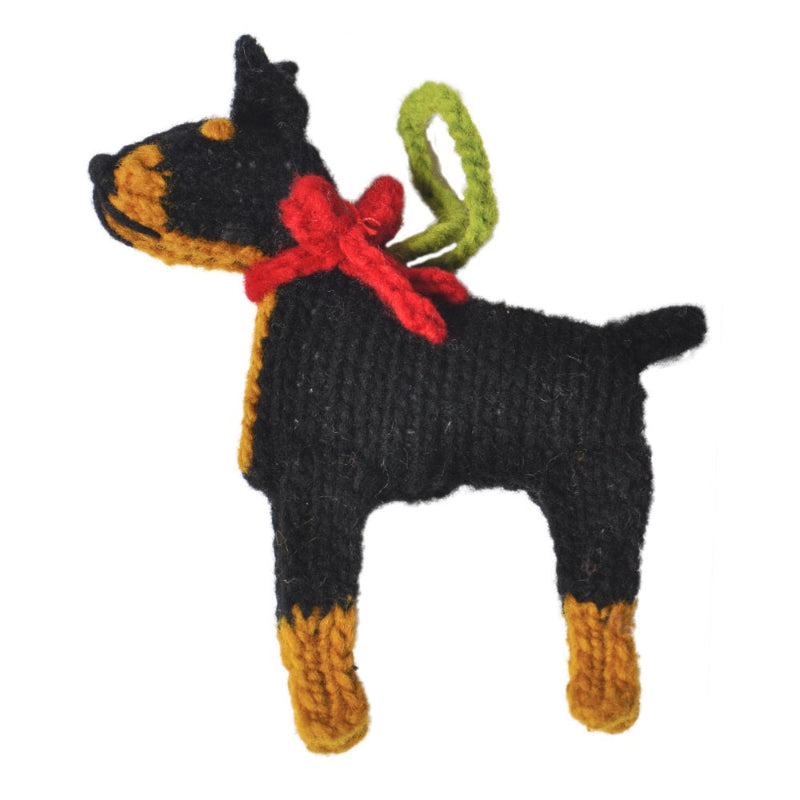 Knitted Doberman Ornament with a red bow and green tag on a white background