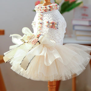 Dog dress with floral embellishments and a bow on a mannequin against a blurred indoor background.