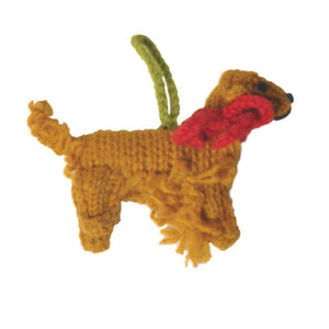 A knitted Golden Retriever ornament in golden brown with a bright red collar and a green hanging loop, shown on a plain white background.