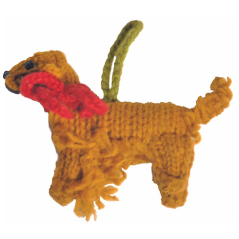 Knitted Golden Retriever ornament with a red bow on a white background