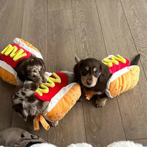 Dachschund puppies  wearing hot dog-themed costume on a wooden floor.