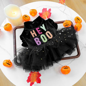 Black Halloween-themed outfit with 'HEY BOO' text on a white surface with decorative pumpkins and leaves.