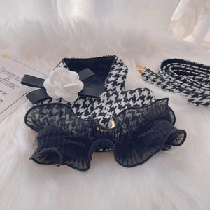 Black and white houndstooth patterned dog collar with a white flower on a white surface.
