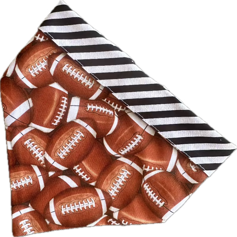 Handmade in the USA by Chloe &amp; Max, this reversible Football Bandana features footballs, with white and black striped trim and backing.