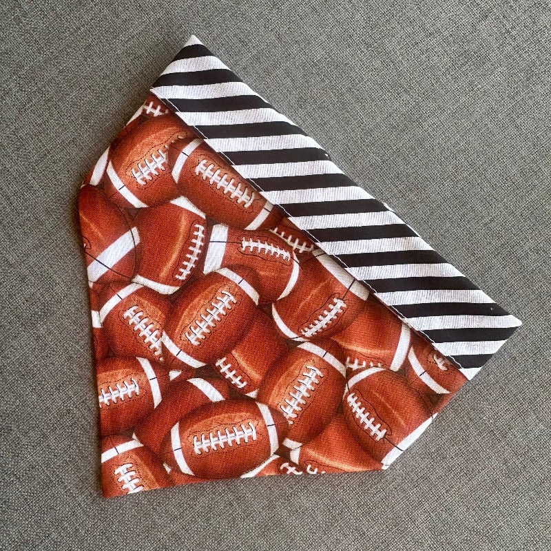 Handmade in the USA by Chloe &amp; Max, this reversible Football Bandana features footballs, with white and black striped trim and backing.