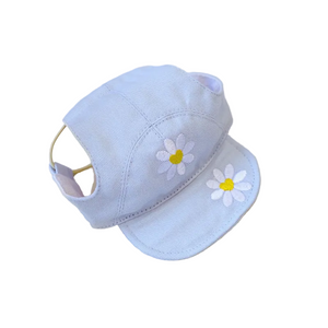 Light blue cap with white daisy flowers on a textured beige surface