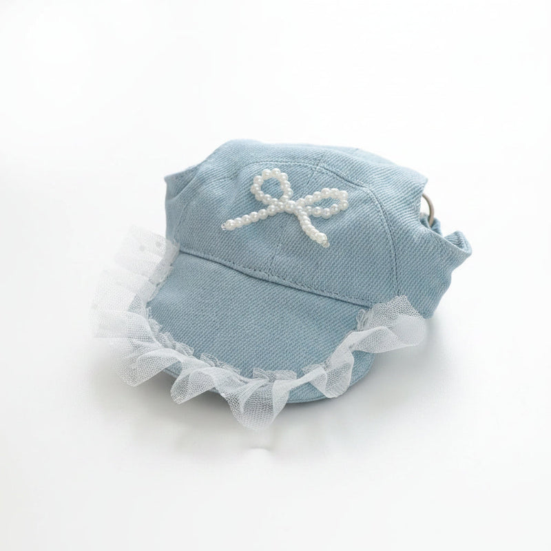 Light blue cap with white lace and bow on a wooden surface
