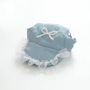 Light blue cap with white lace and bow on a wooden surface
