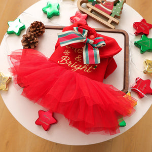 Red Christmas-themed outfit with tutu skirt on a white surface with decorative items.