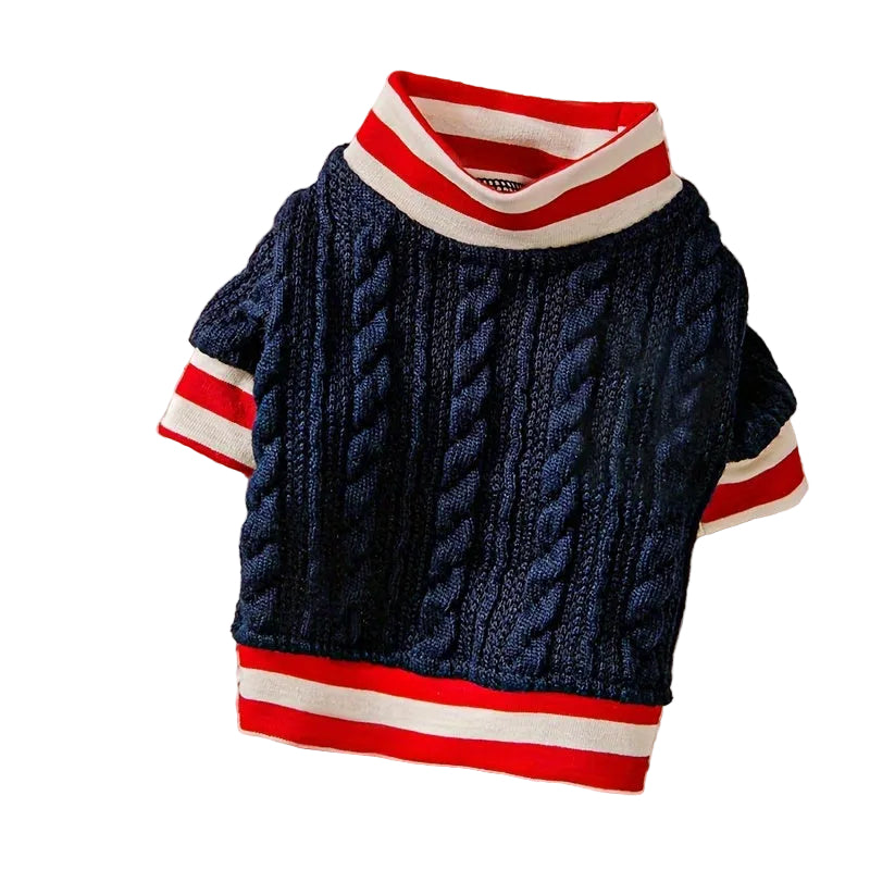 Navy blue cable knit sweater with red and white stripes on a textured surface.