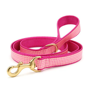 Pink checkered dog leash with a gold clasp on a white background