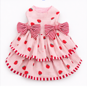 Pink dress with red strawberry patterns and large bows on a white background