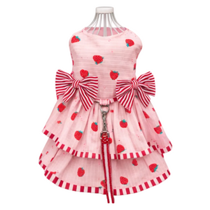 Pink dog dress with strawberry pattern and large bows on a mannequin against a white background