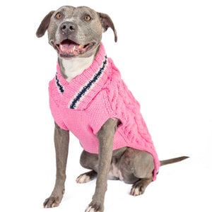 A gray pitbull wearing a pink knit sweater vest with a V-neck and dark trim, photographed against a plain white background.