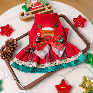 Red dress with reindeer design on a wooden tray surrounded by Christmas decorations.