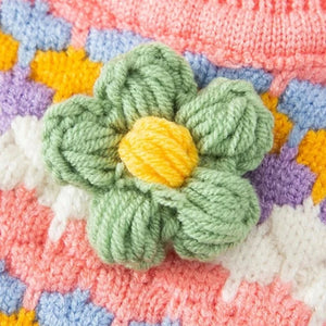 Handmade knit sweater is adorned with a wool flower .