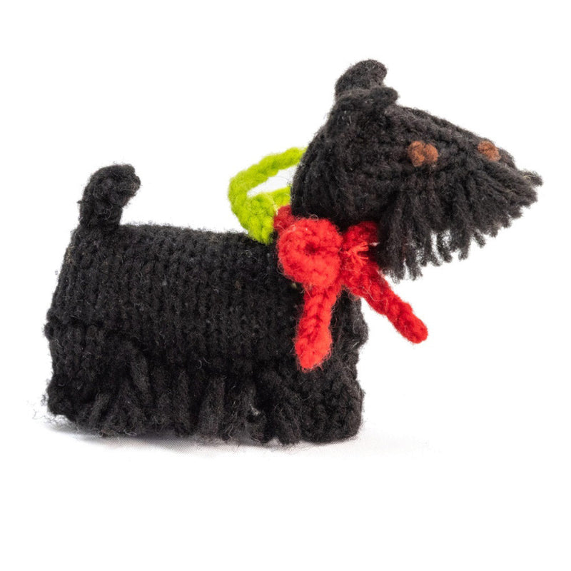 Black crocheted dog toy with a red bow and green tag on a white background
