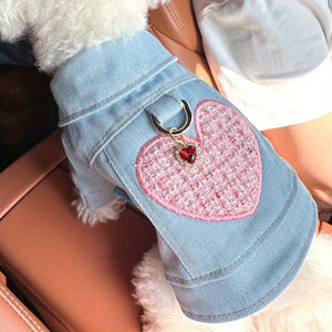 Denim jacket with a pink heart-shaped patch and charm.