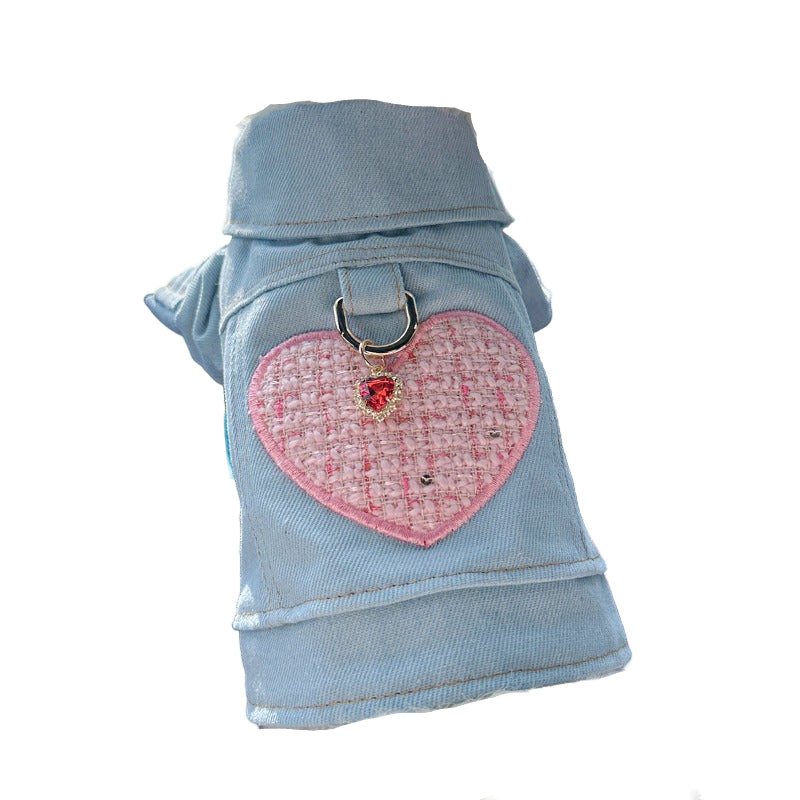 Dog wearing a light blue denim jacket with a pink heart design on a white background