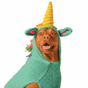 Dog wearing a colorful unicorn costume with a yellow horn and green body on a white background
