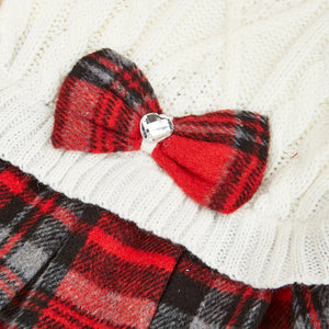 Close-up of a red and black plaid bow on a white cable knit dog sweater