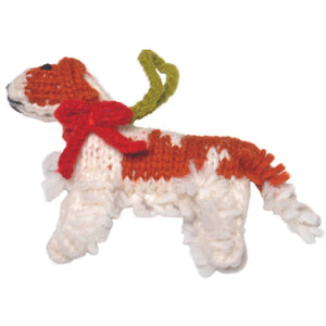 Knitted Cavaier dog ornament with red bow and green tail on a white background