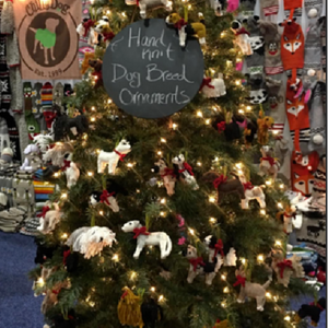 Decorated Christmas tree with hand-knit dog bread ornaments and a sign indicating their handmade nature.
