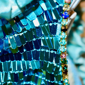 This C'Mimi Designer Couture Ariel Dog Party Dress features glittering aqua rectangular sequins and multicolored rhinestone trim sleeves. 