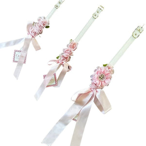 Perfect for weddings, these stunning light pink silk flowers on a faux white leather collar feature a matching pink satin bow. 